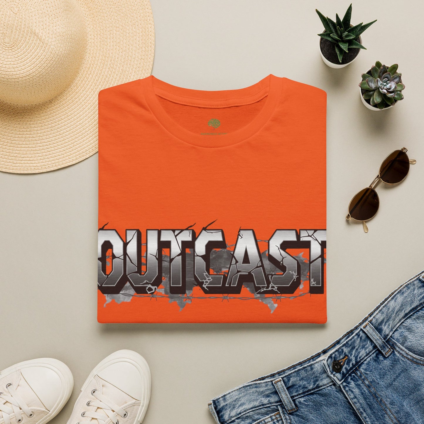 An orange folded T-shirt with a large 'OUTCAST' graphic across the front.