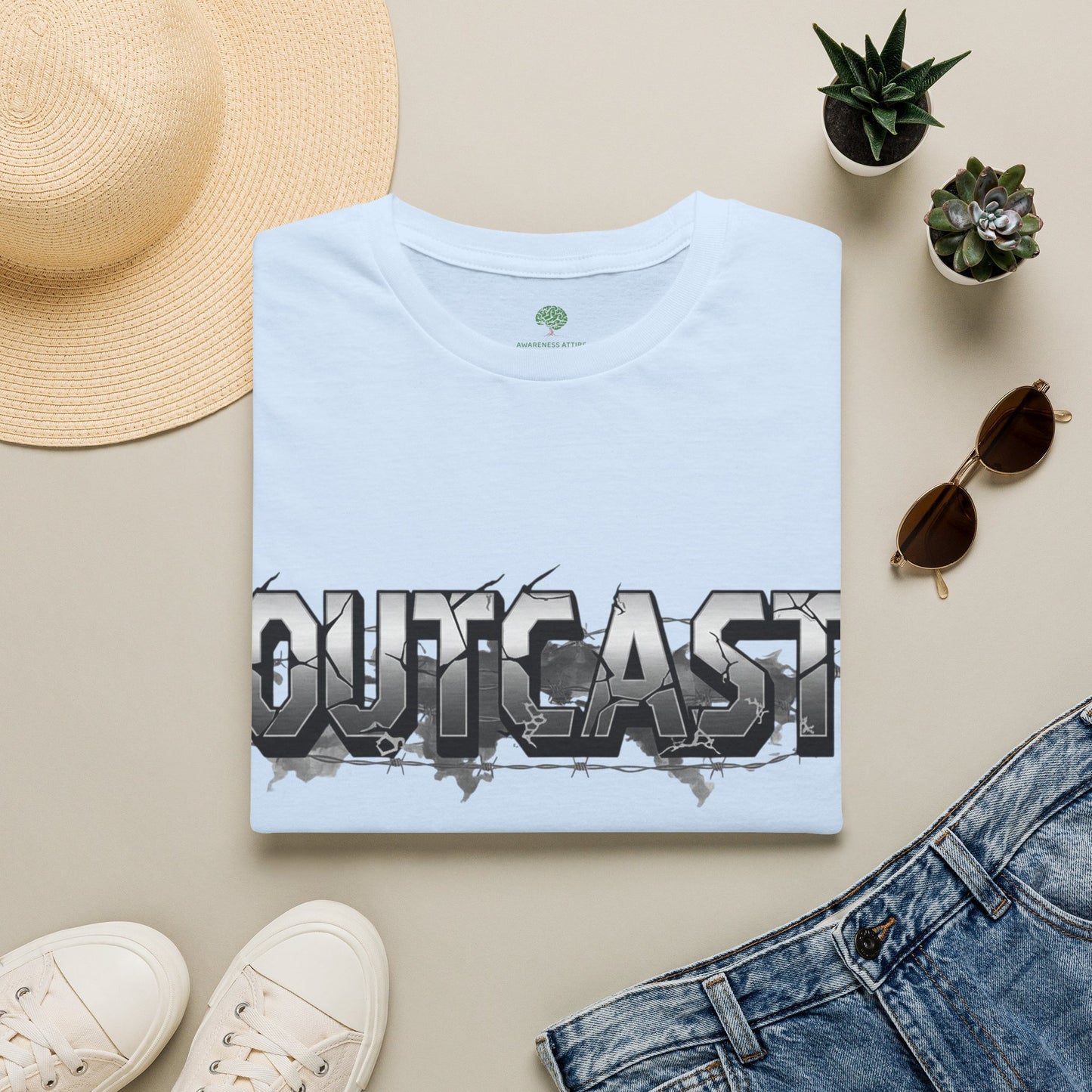 A folded light blue T-shirt with a large 'OUTCAST' graphic across the chest
